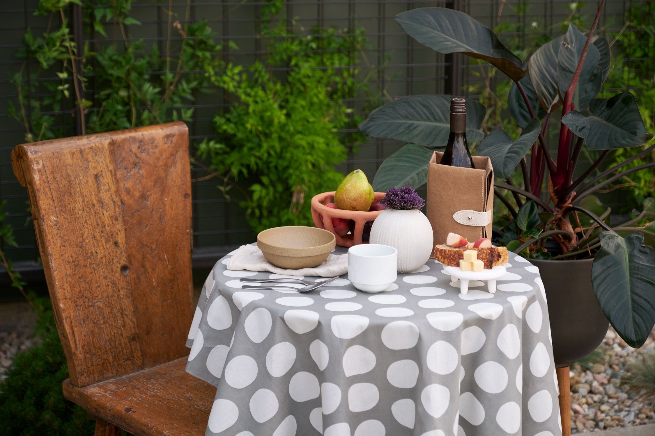 Outdoor setting with a table set for a meal, featuring dishware from  Tina Frey Designs, Virginia Sin, Uashmama, and Hasami Porcelain