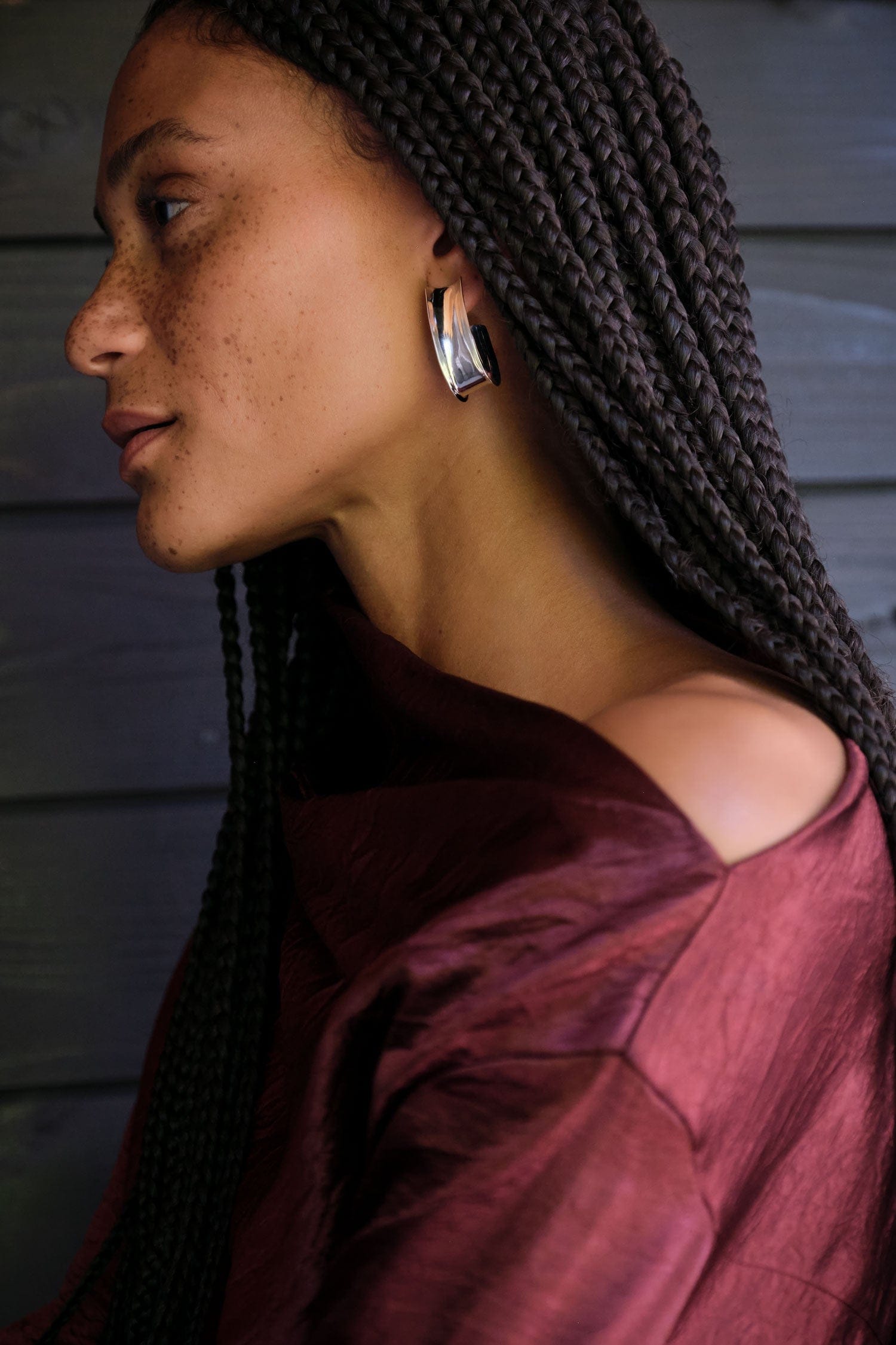 Woman with braided hair wearing a Lauren Manoogian Lustre Top with Fay Andrada silver hoop earrings against a neutral background