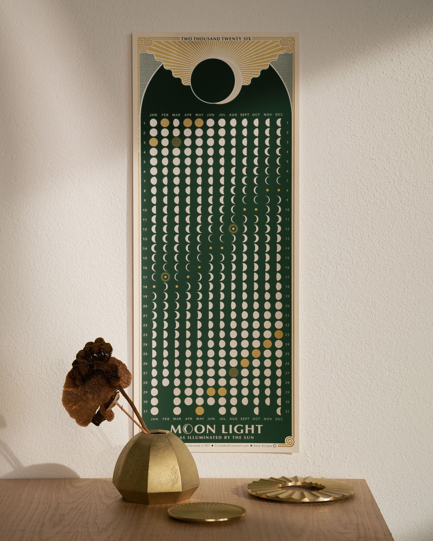 Featured gift ideas of decorative wall poster of moon phases on a white wall with a wooden table in the foreground. 