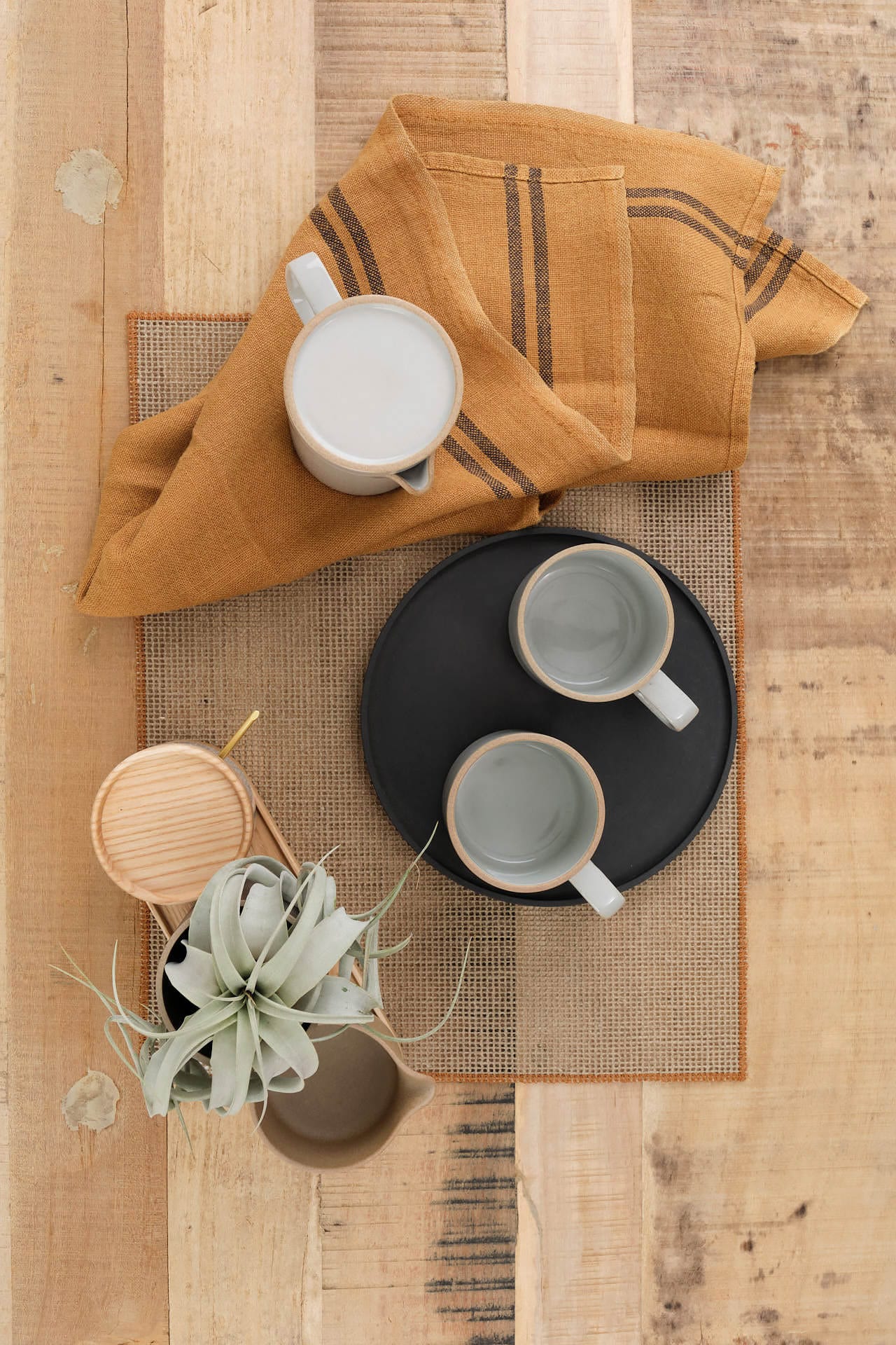 Hasami Porcelain Ceramic mugs on a wooden surface with a mustard-colored napkin and small plant.