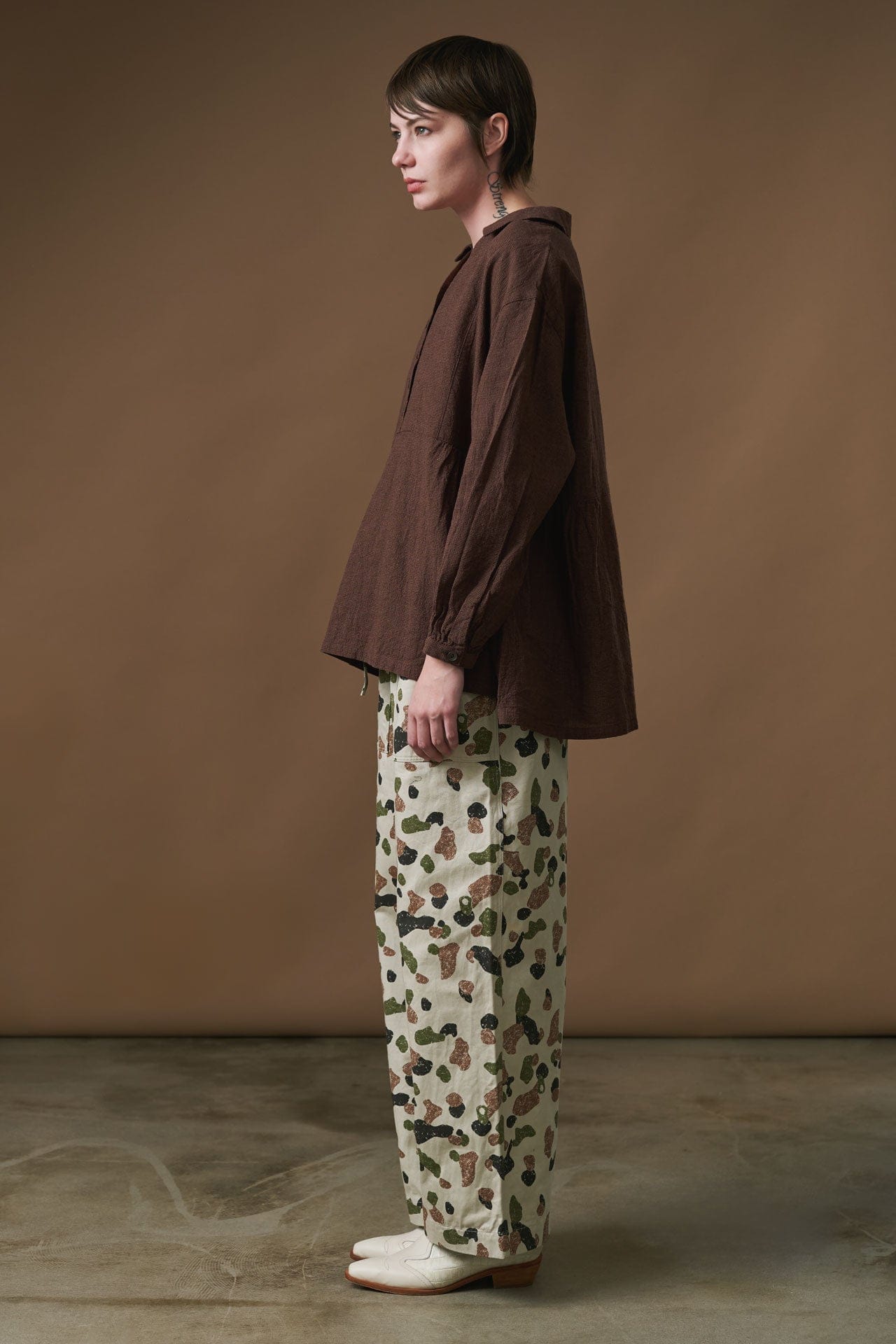 Person wearing Ichi Antiquities brown shirt and patterned pants against a beige background