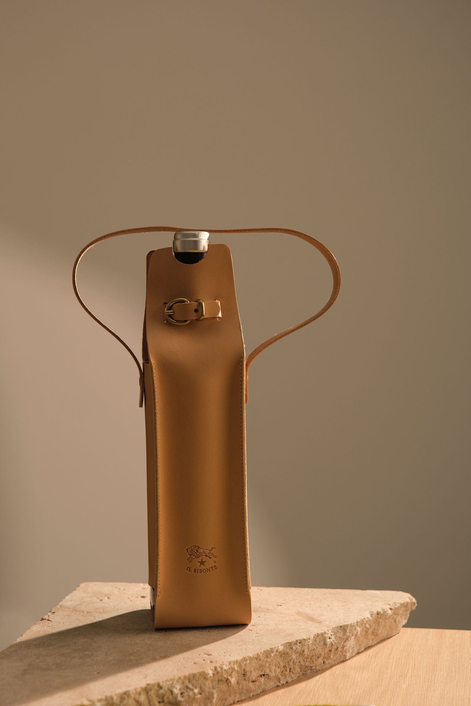 Brown leather bag by Il Bisonte with metal clasp on a stone surface against a plain background