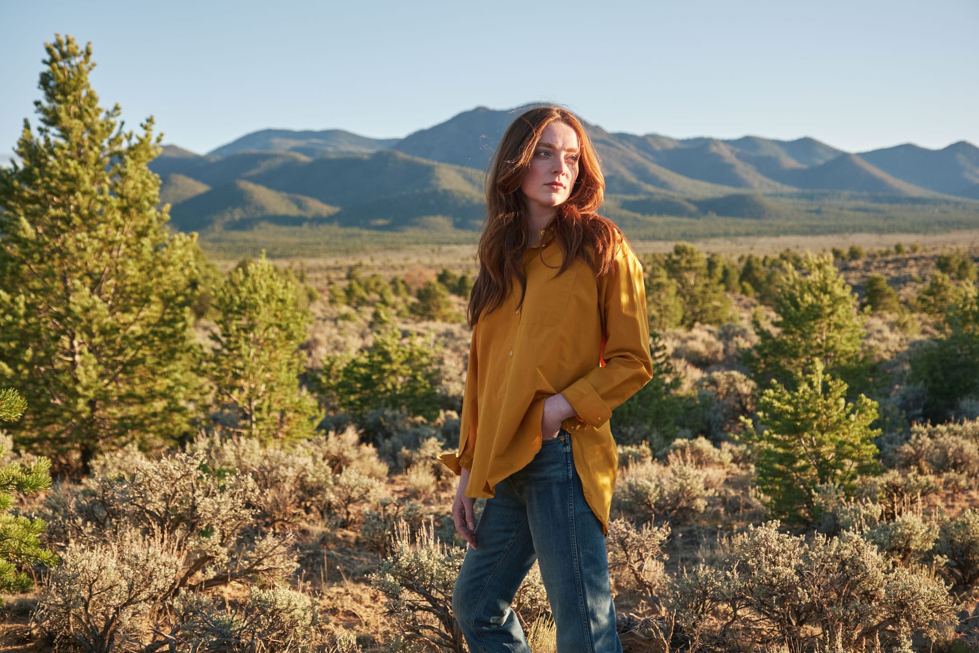 Woman standing in a desert landscape wearing Jamie Haller shirt and Jamie Haller jeans with mountains in the background