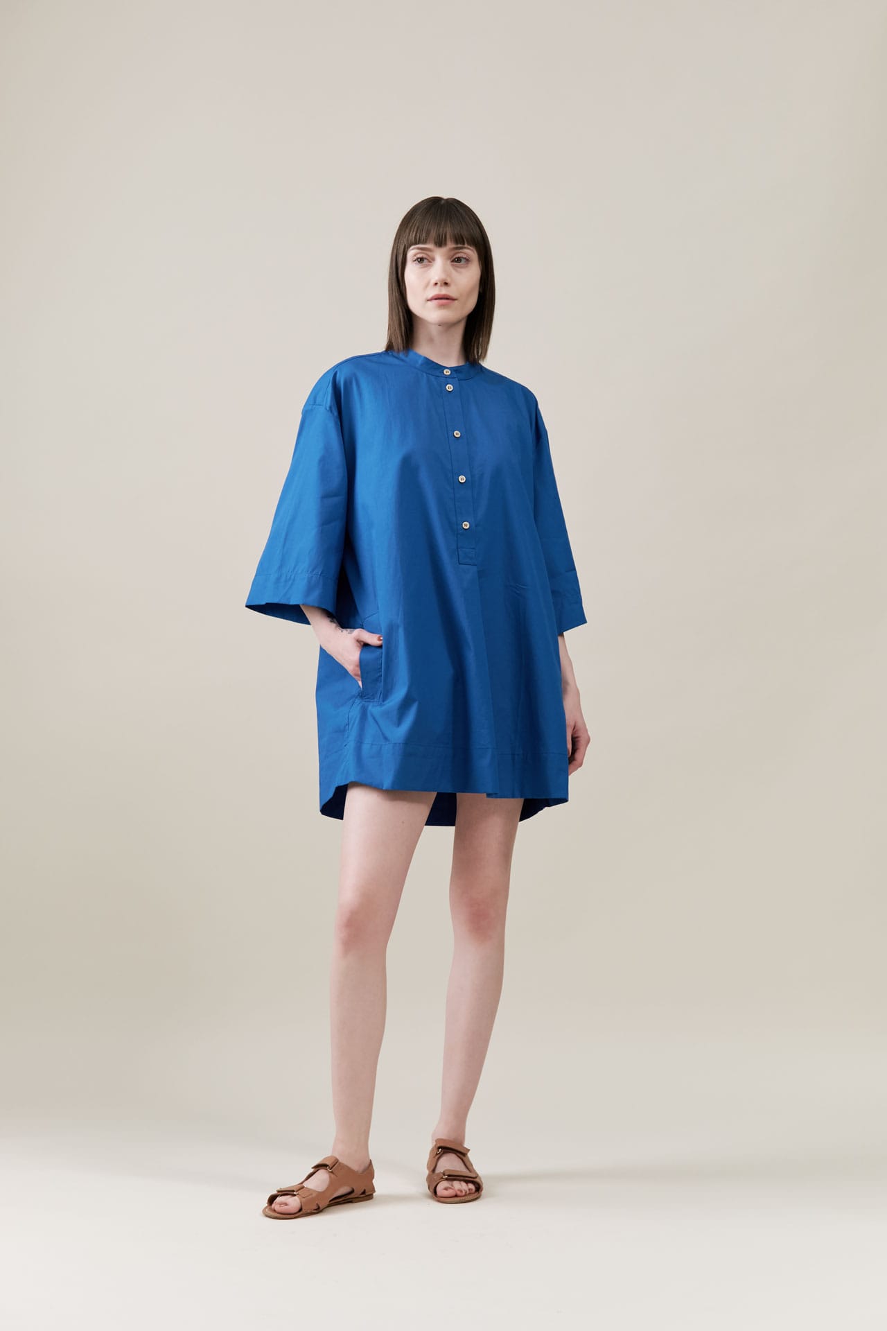 Woman wearing a blue dress by Jamie Haller on a beige background