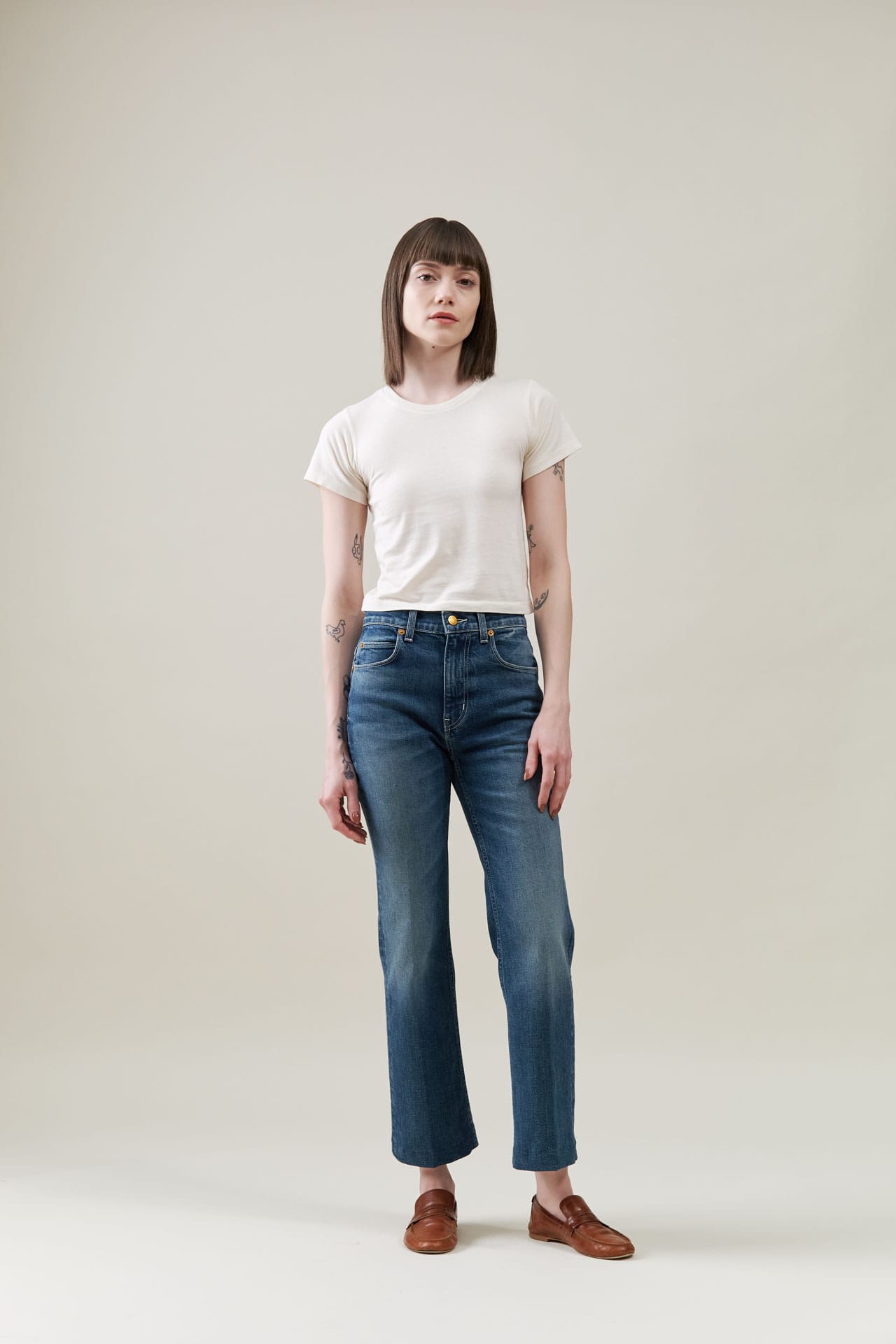 Person wearing a Atelier Delphine baby white t-shirt and jamie haller blue jeans on a plain background