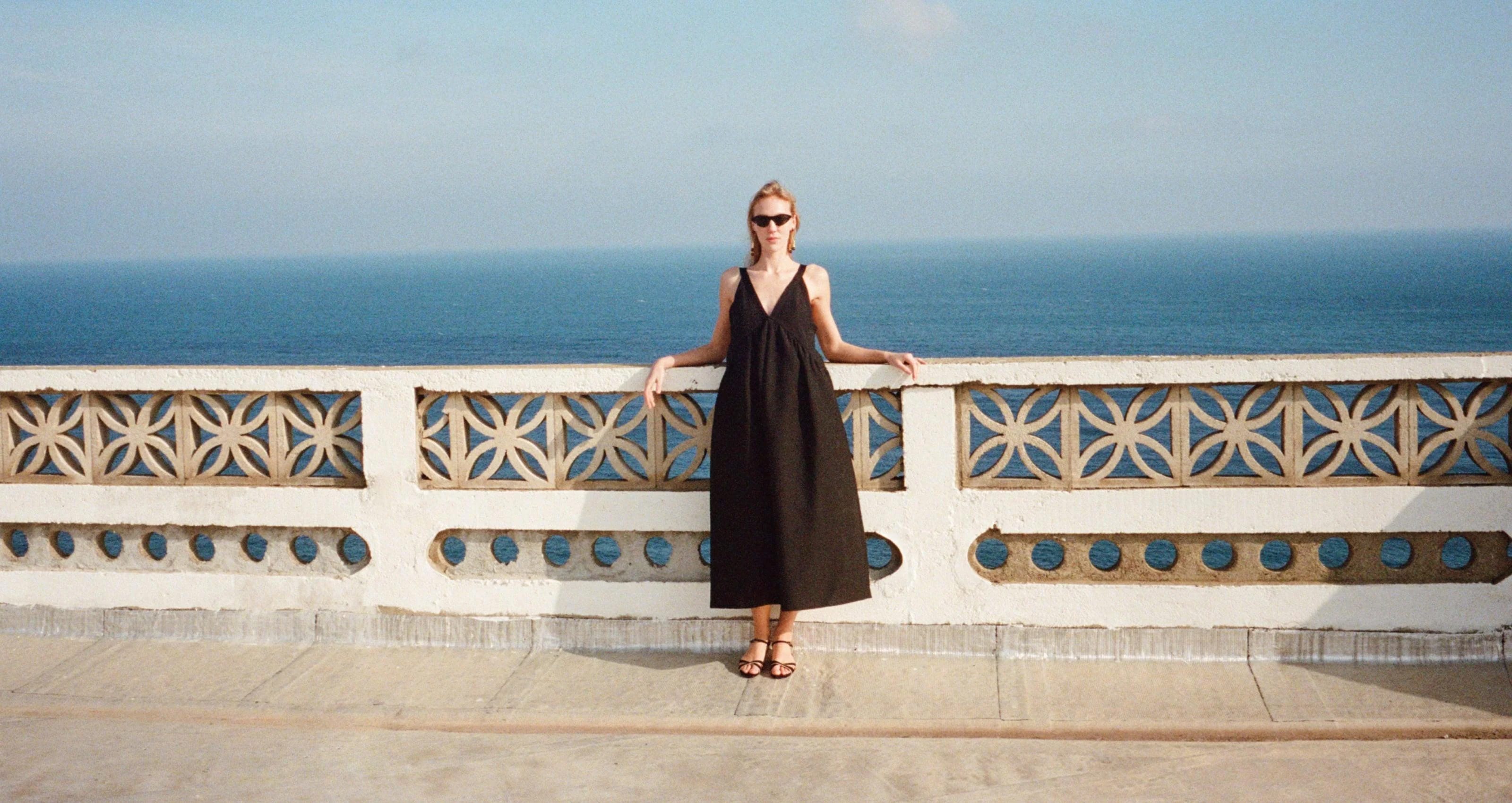 Woman wearing Rachel Comey oversized black dress standing on a balcony overlooking the 